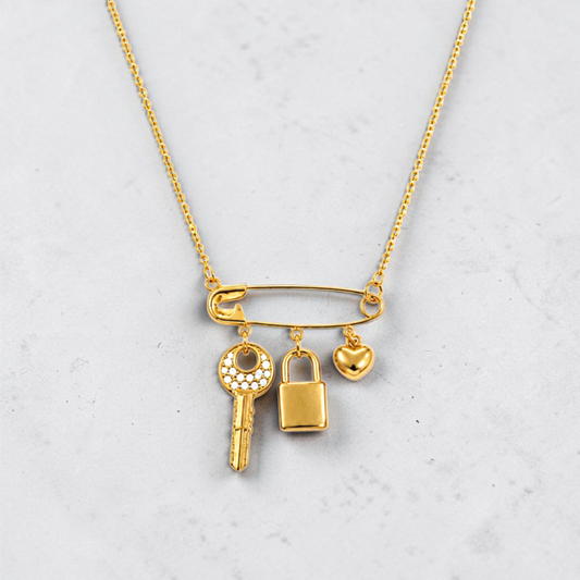 18k gold plated safety pin necklace with heart, lock, and crystal key charms in tarnish-free stainless steel.