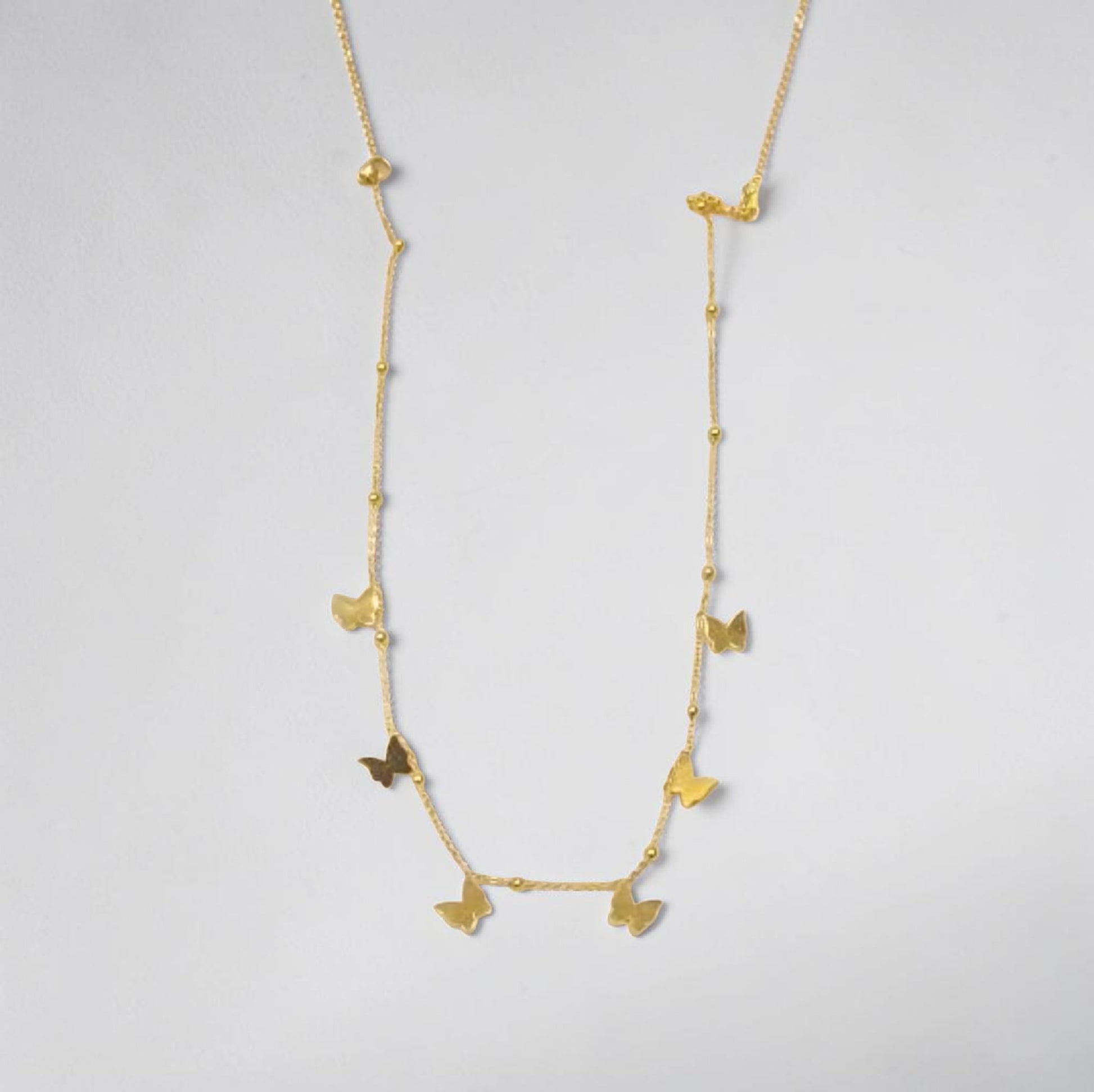 Gold necklace with butterfly pendants on a light gray background | Butterfly Necklace 18k gold plated water proof and stainless steel by Efforro Pakistan 