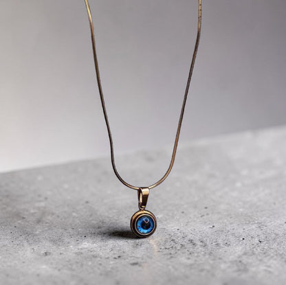 Evil Eye Necklace with a blue eye pendant on a gray surface 